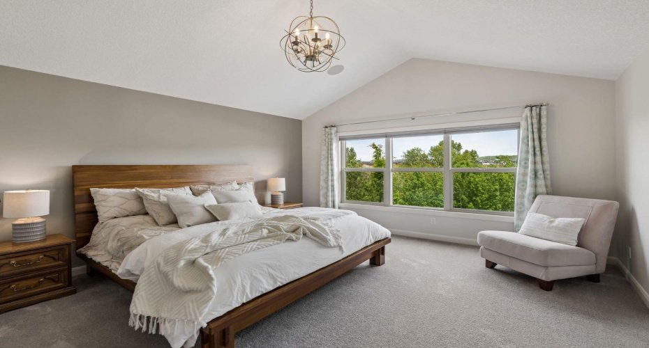 The spacious primary suite offers a peaceful escape, complete with vaulted ceilings, abundant natural light, and tranquil views overlooking the river valley with glimpses of the Rockies in the west.
