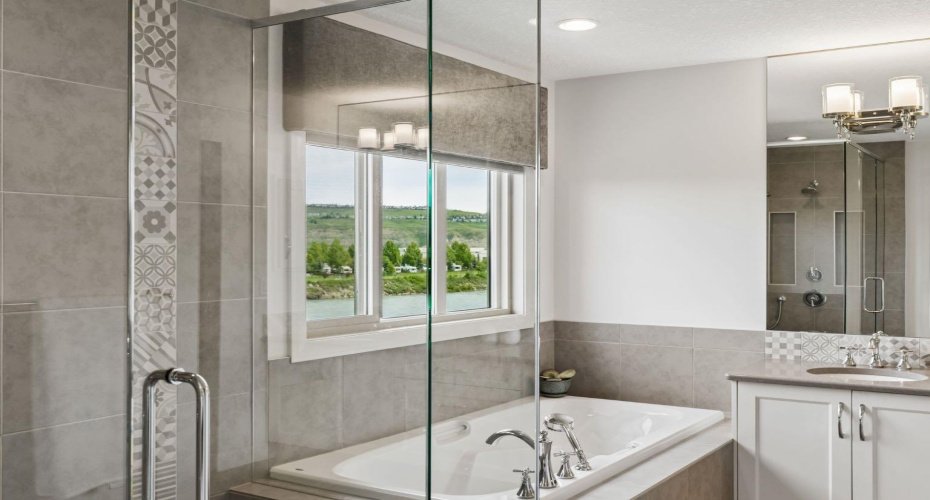 The luxurious ensuite combines comfort and functionality, featuring a deep soaker tub positioned beside large windows that bring natural light and scenic views into your daily routine.