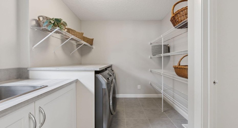 Upper Floor Laundry thoughtfully positioned between the Primary Retreat and Main Living Area, complete with Built-In Shelving and a Utility Sink for added convenience and everyday functionality.