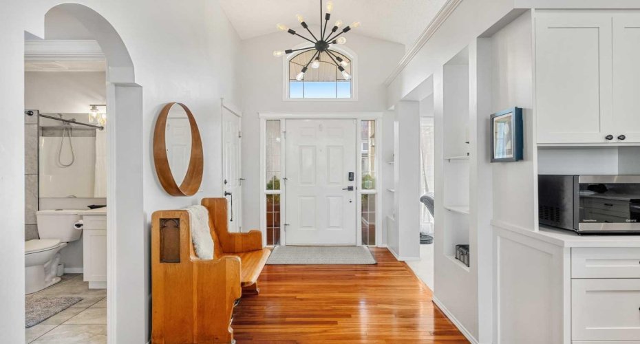 From the front foyer, you’re greeted by soaring vaulted ceilings, hardwood flooring, and a clear line of sight to the living area.