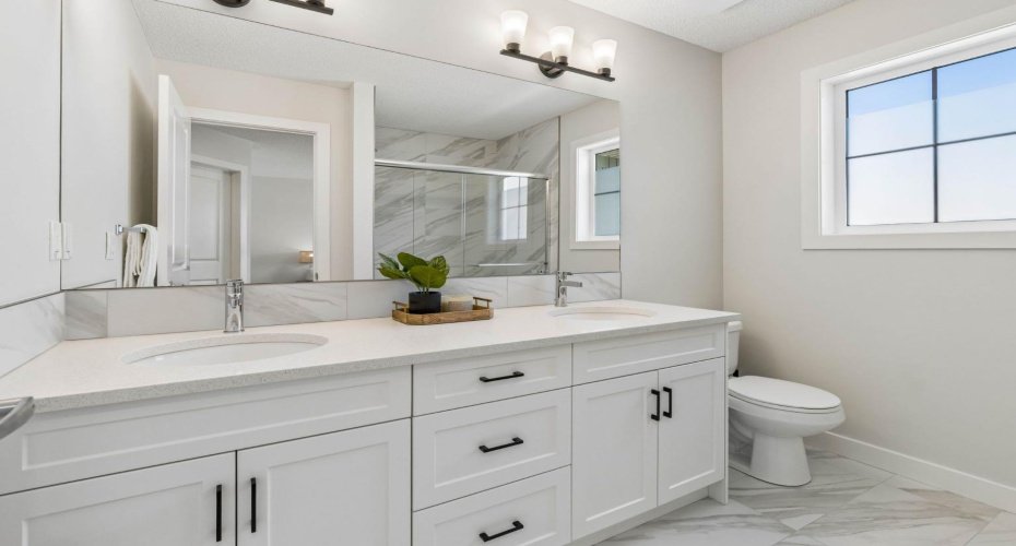 Start your mornings with ease in this beautifully finished ensuite featuring dual vanities, quartz countertops, elegant tilework, and plenty of room to simplify busy routines.