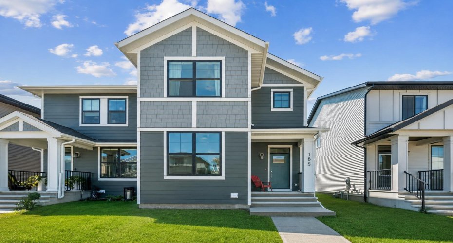 Welcome home to 185 Emberside Hollow, where timeless curb appeal and modern design create an inviting first impression. Situated on a sunny corner lot, this beautifully designed home offers contemporary architecture, a welcoming front porch, and a family-friendly streetscape in the heart of desirable Fireside. (Lawn has been modified digitally to show potential of grass being completed )Clean lines, striking curb appeal, and thoughtful craftsmanship define this beautiful Cardel-built home. The welcoming façade and charming covered entry set the tone for the stylish and functional spaces waiting inside.
