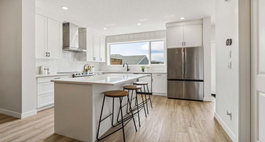 The heart of the home is a bright, thoughtfully designed kitchen featuring crisp white cabinetry, quartz countertops, stainless steel appliances, and a large island that naturally brings everyone together.