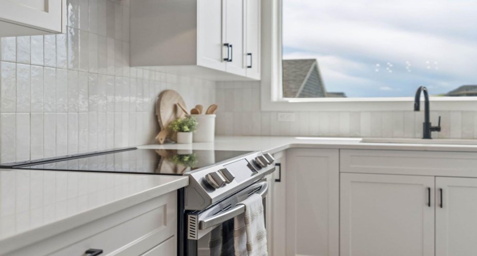Thoughtfully appointed with timeless finishes, this chef-inspired space features sleek quartz countertops, crisp white cabinetry, a modern tile backsplash, and an abundance of prep space for every occasion.