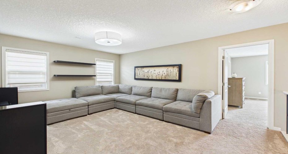The inviting upstairs bonus room offers flexible living space, creating the perfect retreat for movie nights, quiet evenings, or winding down before bedtime.