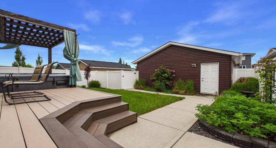 Backyard: Beautifully landscaped and meticulously maintained backyard featuring a low-maintenance fence and durable composite decking, designed to withstand harsh weather conditions while providing an attractive and functional outdoor living space