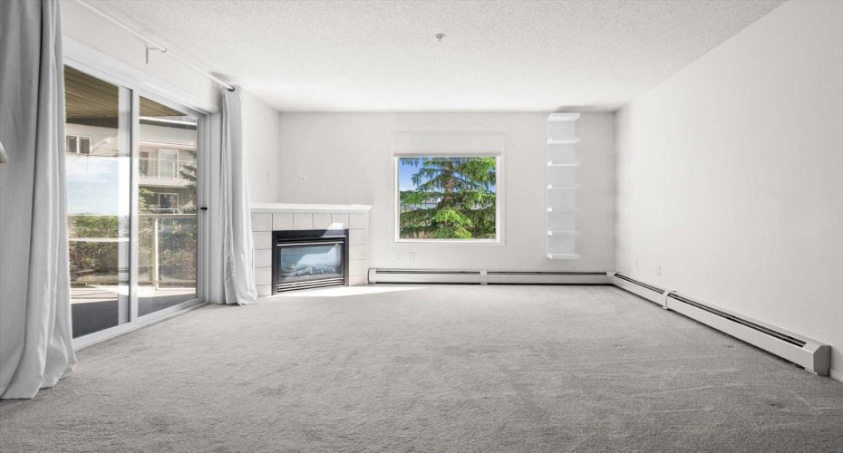 Bright sunny living room with gas fireplace and access to the balcony