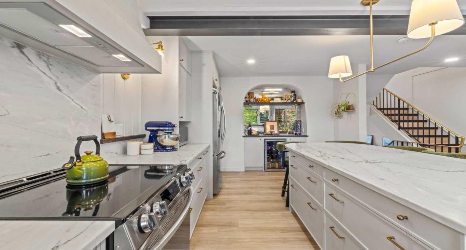 A view of the kitchen from the window. Look at the large island, those stunning Rosa Aurora Marble countertops, and the brass accents.