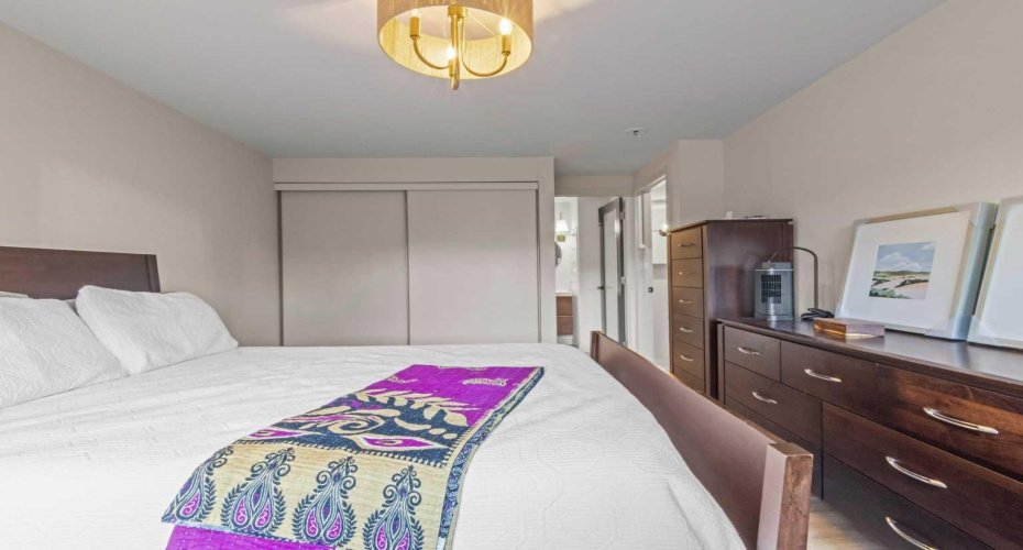 There is plenty of room for large furniture in this primary suite. Note the light fixture over the bed continuing with the brass accents throughout this home.