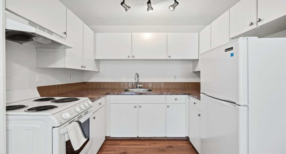 All white cabinets and well maintained appliances with an LVP floor