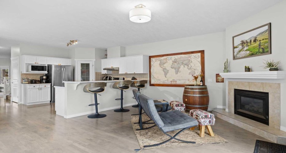 The inviting living room centres on a tiled gas fireplace, with bar seating and warm natural light creating a relaxed, social feel.