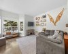 A comfortable front family room bathed in natural light from oversized windows, with rich hardwood underfoot.
