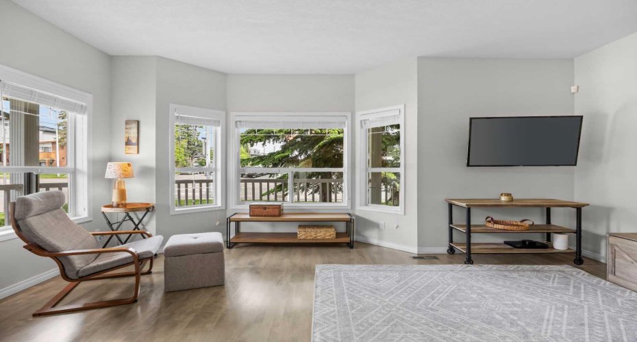 Oversized bay windows wrap this living space in light, offering leafy street views and a calm, airy atmosphere.