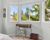 A peaceful corner sitting nook in the primary bedroom, framed by bright windows and treed neighbourhood views.
