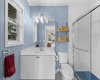 The crisp three piece ensuite features a walk in glass shower, quartz topped vanity, and a cheerful, light filled palette.