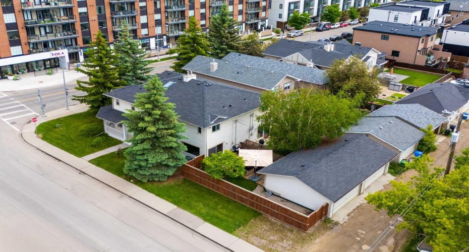 An aerial view captures the home's standout corner lot, fully fenced yard, and prime position beside the shops of Marda Loop.