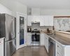 The kitchen pairs crisp white cabinetry with full stainless appliances, a glass paned pantry door, and warm wood flooring throughout.