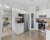 A bright, functional layout with abundant cabinet storage and a glass pantry, flowing seamlessly toward the living room beyond.