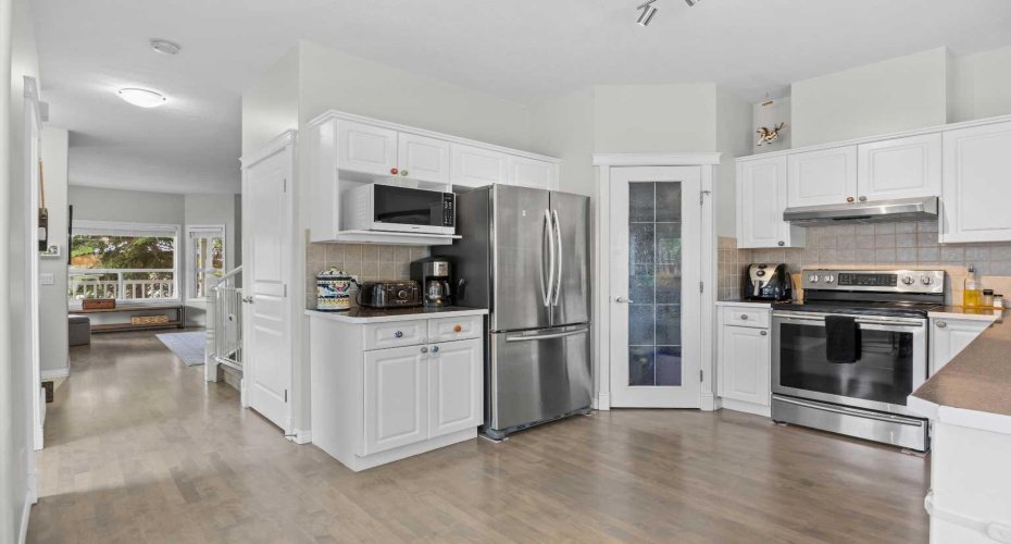 A bright, functional layout with abundant cabinet storage and a glass pantry, flowing seamlessly toward the living room beyond.