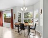 The sunny dining area sits in a bright bay window with a designer chandelier above.
