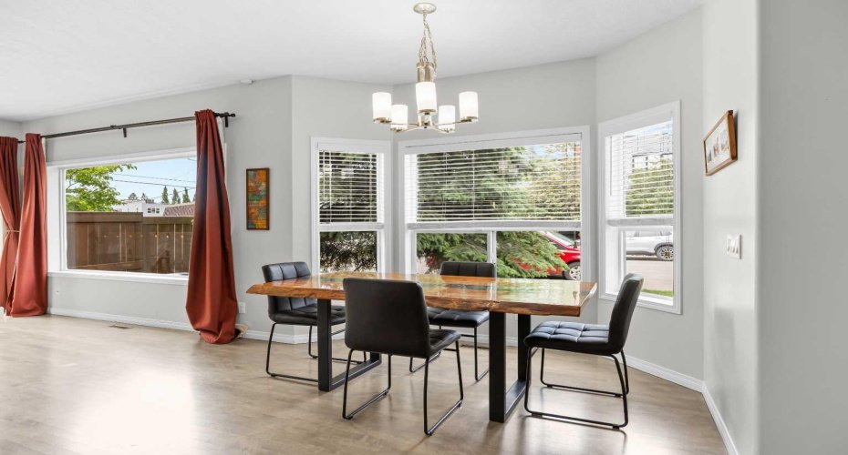 The sunny dining area sits in a bright bay window with a designer chandelier above.
