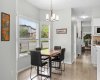 Wide plank flooring and crisp white trim carry the eye down the hall, connecting the dining space to the front of the home.