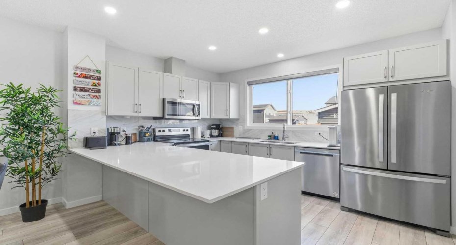 Big sized kitchen that has a breakfast bar, and double door refrigerator