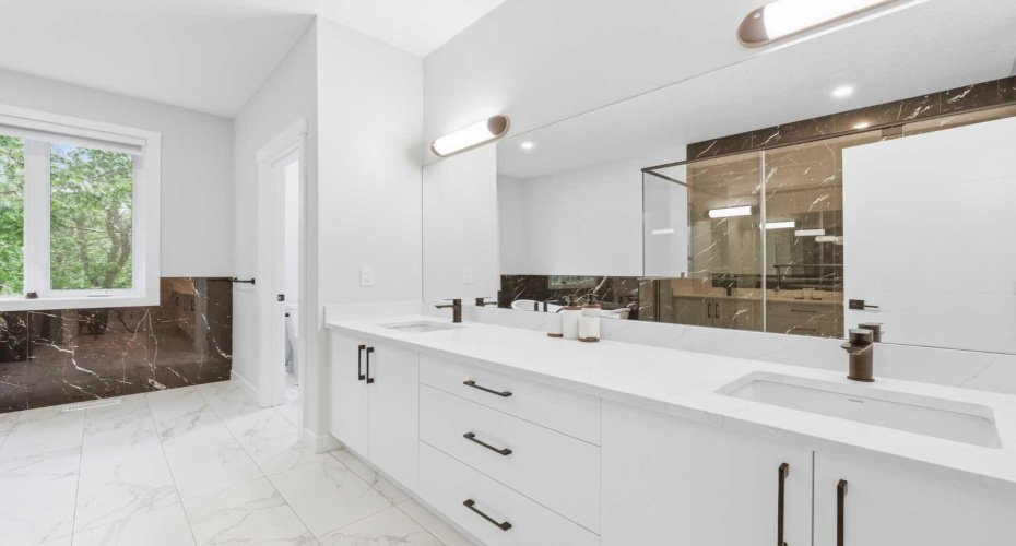 Elegant ensuite features dual vanities and refined designer finishes throughout.