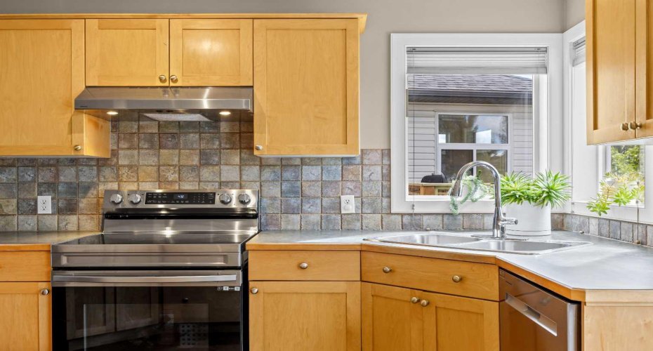 Stainless steel appliances, a tile backsplash with character, and a sunny window over the sink — the little things that make the everyday routine feel a bit brighter.
