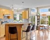From the breakfast bar, the kitchen opens straight into a dining nook wrapped in windows — the sightlines here mean nobody ever eats alone.