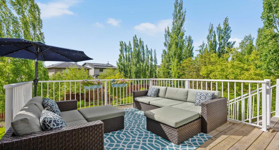 The upper deck overlooks all that backyard greenery — already set up for morning coffees, evening wind-downs, and the kind of nights that run longer than planned.