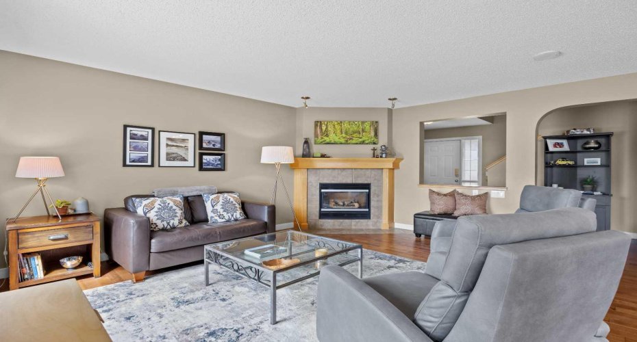 The living room brings genuine warmth, with updated hardwood floors, soaring ceilings, and a corner gas fireplace anchoring the space.