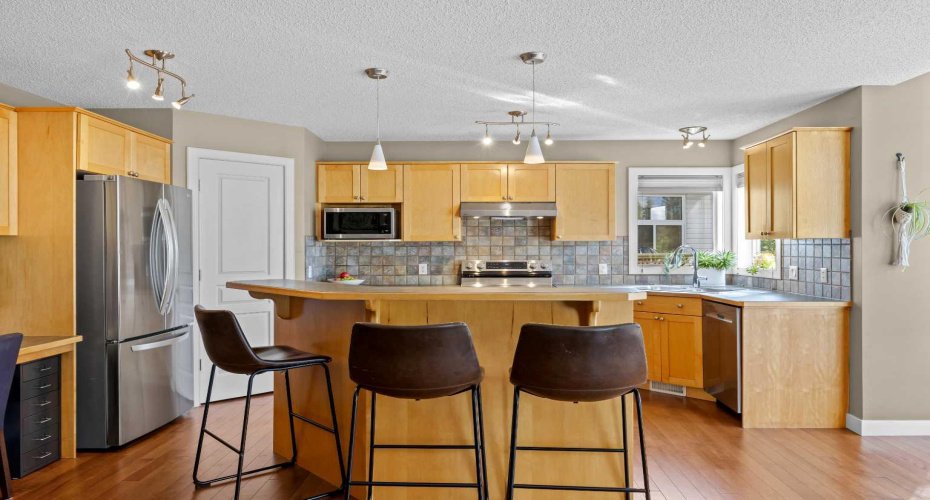 The kitchen is well-proportioned and practical, with stainless steel appliances, a corner pantry, and a raised breakfast bar that quietly becomes homework central, snack headquarters, and the best seat in the house.