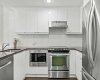 Stainless steel appliances, a built-in microwave, and full-height cabinetry against a clean tiled backsplash — a space that feels intentionally finished.
