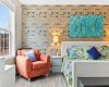 Tucked beside the window, a reading chair and warm lamplight make the perfect spot to slow down. The layered brick wall gives the whole suite an unexpected, boutique-hotel feel.