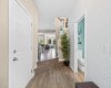 The front door opens to a bright, welcoming foyer with rich wide-plank flooring and a convenient main-floor powder room. A few steps up, the home opens into light-filled living — you can already see straight through to the sunny back windows.