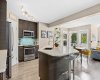 Espresso cabinetry, quartz counters, and a striking teal mosaic backsplash set the tone in this open-concept kitchen. Stainless appliances and an oversized island anchor a space designed for everyday life and easy entertaining.