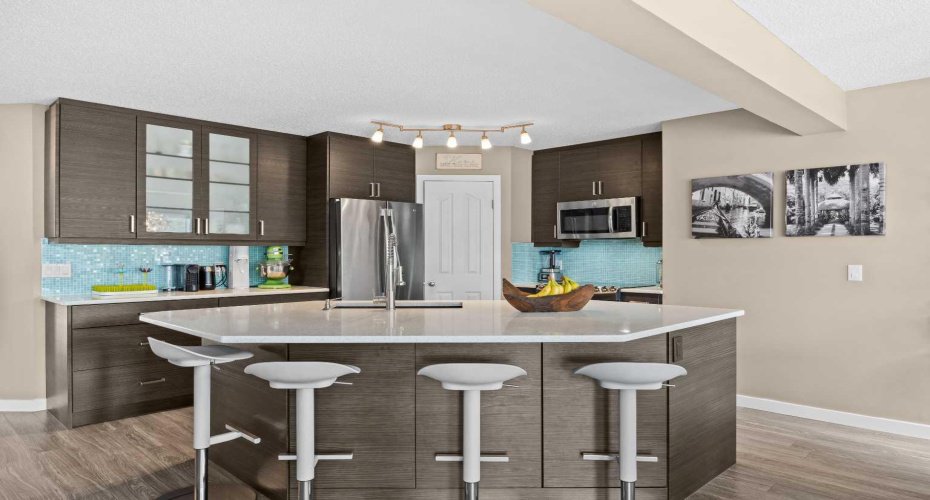 Glass-front uppers, and a generous breakfast bar, this kitchen balances style and function beautifully, with thoughtful lighting overhead and abundant storage throughout.