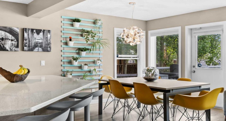 A statement pendant and a vertical garden wall frame a dining space made for lingering. Just beyond, the back door opens to your outdoor living — coffee in the morning, dinners al fresco at night