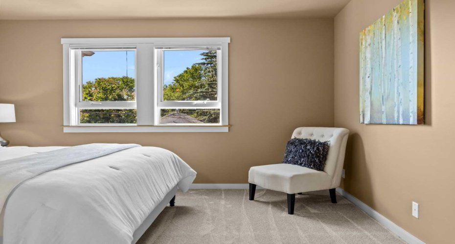 The primary bedroom offers a peaceful, light-filled retreat with a tree-lined window view.