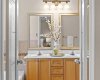 French doors open into the primary ensuite, revealing a double vanity with plenty of counter space and a well-lit mirror for morning routines.
