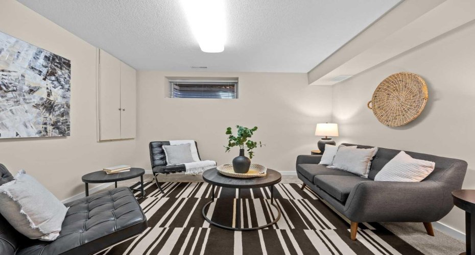 A flexible lower-level bedroom doubles as a bonus or TV room, offering comfortable seating and soft lighting.