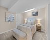 This bright lower-level bedroom pairs soft neutral tones with a large window for natural light.
