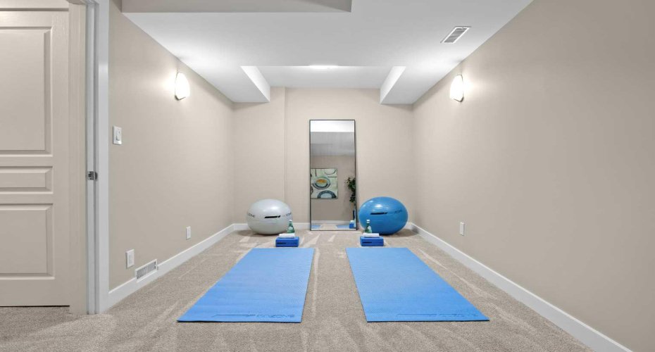 A dedicated flex room downstairs is set up as a home gym, with plenty of space for mats, equipment, and a full-length mirror.