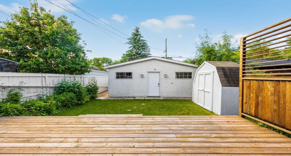 The rear yard's tidy lawn and storage shed lead to the detached garage, offering practical outdoor space just steps from the deck.