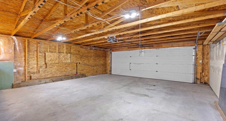 The spacious garage interior shows ample room for two vehicles, lots of room to park a 1/2 ton truck, plus space for storage and workshop use.