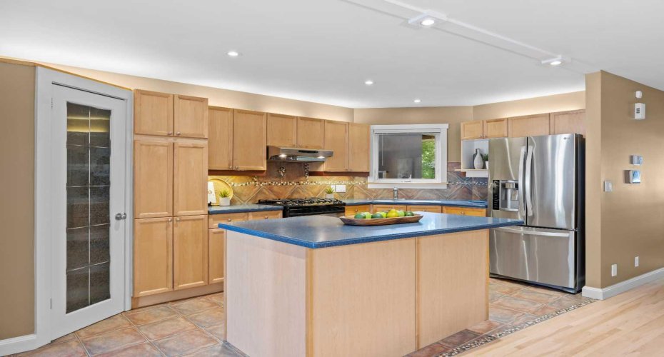 The kitchen island offers extra prep space and a natural gathering spot, just steps from the pantry and fridge.