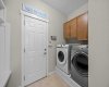 The well equipped laundry room includes upper cabinetry for extra storage, keeping everyday essentials organized and out of sight. The well equipped laundry room includes upper cabinetry for extra storage, keeping everyday essentials organized and out of sight.