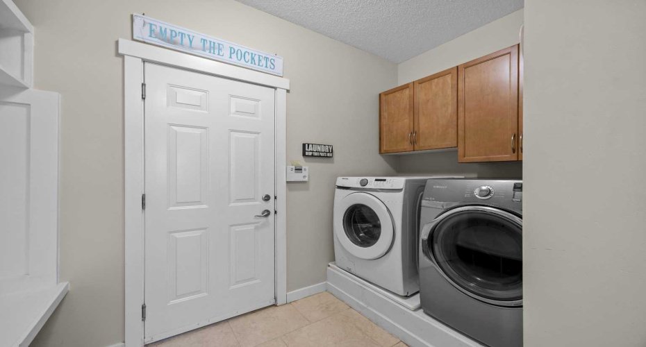 The well equipped laundry room includes upper cabinetry for extra storage, keeping everyday essentials organized and out of sight. The well equipped laundry room includes upper cabinetry for extra storage, keeping everyday essentials organized and out of sight.