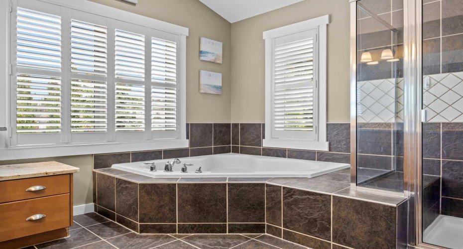 A deep corner soaker tub framed by tiled walls and natural light invites you to unwind after a long day. A deep corner soaker tub framed by tiled walls and natural light invites you to unwind after a long day.